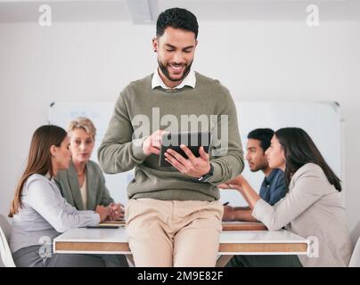 Wir setzen Technologie ein, um unsere Ziele voranzubringen. Ein junger männlicher Geschäftsmann, der während eines Meetings ein digitales Tablet benutzt. Stockfoto