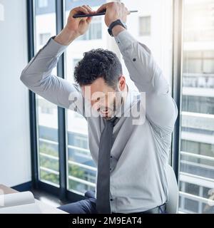 Warum funktioniert heute nichts? Ein junger Geschäftsmann, der sein Notebook bei der Arbeit zerschmettert. Stockfoto