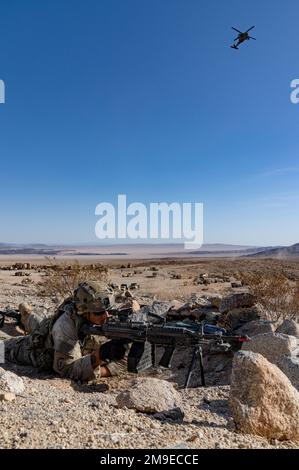 USA Nikolas Garcia, ein Infanterist, der dem Regimentalen Hauptquartier und Hauptquartier des 3D. Kavallerie-Regiments zugeteilt wurde, scannt das Gelände und sorgt für Sicherheit während eines taktischen Standortwechsels oder ‚Sprungs‘ am 18. Mai im National Training Center, Fort Irwin, Kalifornien. Über Kopf, Soldaten des 3. Angriffs-Helikopter-Bataillons, 4. Kampfluftfahrtbrigade, 4. Infanteriedivision, fliegen einen UH-64 Blackhawk in der Nähe der Bodeneinheit, um feindliche Aktivitäten zu suchen. 3D CR und die zugehörigen Hilfsaggregate führten im Laufe des Monats eine Rotation der Schulung durch Stockfoto
