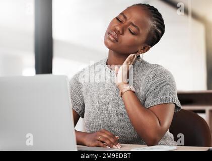 Heute ging es in eine ganz andere Richtung. Eine junge Geschäftsfrau, die gestresst wirkt, während sie ein Notebook an ihrem Schreibtisch in einem modernen Büro verwendet. Stockfoto