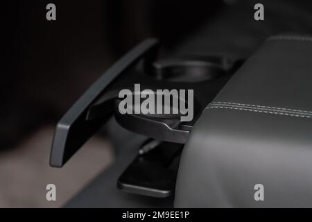 Moderner Getränkehalter für Fahrzeuge in der hinteren Sitzreihe. Armlehne im Auto mit Getränkehalter. Stockfoto