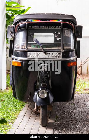 Colombo, Sri Lanka - 4. Dezember 2021: Schwarzes Bajaj Tuk Tuk steht an einer Straße, Vorderansicht Stockfoto