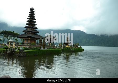 Ein malerischer Blick auf Pura Ulun Danu Beratan am Ufer eines Sees in grünen Bergen an einem nebligen Tag in Bali, Indonesien Stockfoto