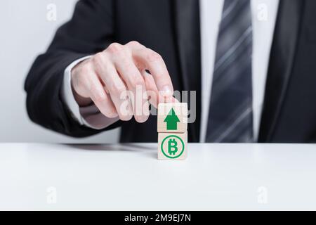 Holzblöcke mit grünem Währungssymbol und grünem Pfeil nach oben. Wachstums- und Abschreibungskonzept. Stockfoto