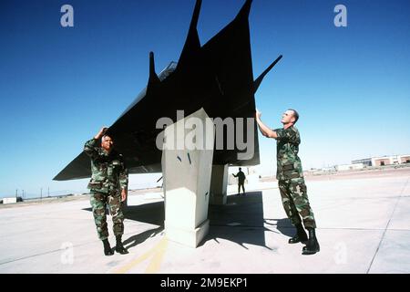 US Air Force MASTER Sergeant Tony Garza (links) und STAFF SGT. Dan Jeffries bereitet ein F-117-Flugzeug für ein Fotoshooting mit Hollomans Diagnostic Imaging Radar vor. Kleine Mängel in der absorbierenden Radarbeschichtung können dazu führen, dass ein Tarnflugzeug auf Radarschirmen erscheint. Die Platten um das Fahrwerk des Düsens sind ebenfalls mit Radar-absorbierendem Material beschichtet, sodass die Radarsignatur des Flugzeugs die gleiche ist, wie sie im Flug wäre. Dieses Foto stammt aus dem Artikel "Now you See it, Now you don't" in der Oktober 1999 Ausgabe des AIRMAN Magazine. Basis: Luftwaffenstützpunkt Holloman Bundesstaat: New Mexico (NM) Land: Vereinigte Staaten Stockfoto