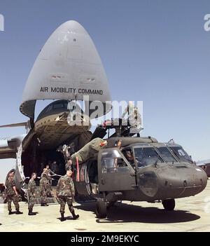 Am Westflughafen Kairo, Ägypten, hilft das Armeepersonal, einen UH-60A Blackhawk Helikopter aus einer Air Force C-5 Galaxy zu entladen. Blackhawk und Armeemitarbeiter kamen in Ägypten an, um den BRIGHT STAR 99/00 zu trainieren. BRIGHT STAR bietet die Gelegenheit, die militärische Zusammenarbeit mit den USA, Ägypten und anderen Koalitionsländern zu verstärken und das gemeinsame Engagement für regionale Stabilität und andere gemeinsame Interessen zu stärken. Die Streitkräfte auf allen Ebenen erhalten die einzigartigen Möglichkeiten, militärische Beziehungen zu stärken und sich mit dem Personal, der Ausrüstung und der Taktik der Koalitionsstreitkräfte vertraut zu machen. Subjekt O Stockfoto