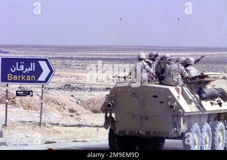Rückansicht rechts – Mittleres Bild eines Cadillac Gage Light Armored Vehicle (LAV) von First LAR (Light Pmored Reconnaissance) Wolfpack Platoon, Camp Pendleton, Kalifornien, Fünf US-Marines sitzen auf der Spitze, während sie eine Straße auf einem ägyptischen Militärstützpunkt entlang zu einem Feuerwehrauto und Manöver während der Brightstar 1999-2000 im Oktober und November in Ägypten fahren. Betreff Betrieb/Serie: BRIGHTSTAR 1999-2000 Land: Ägypten (EGY) Stockfoto