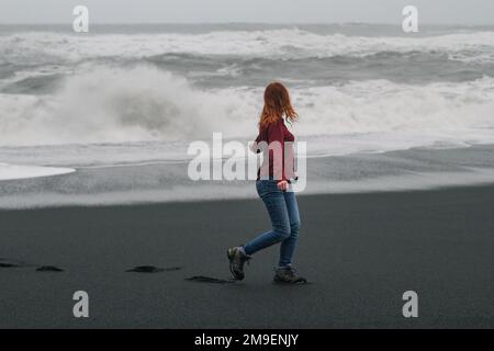 Junge Touristen, die am leeren Strand Islands entlang spazieren gehen und malerische Fotos machen Stockfoto