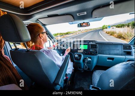 Frau fährt mit einem Wohnmobil oder Wohnmobil in der Natur auf der Straße. Motorheim auf Abenteuerreise mit der Familie oder eine Reise in die Natur auf Kreta, Griechenland. Ausl Stockfoto