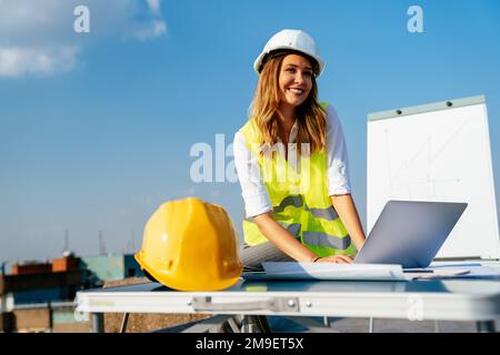 Junge weibliche Bau spezialisierte Techniker Blueprints auf Baustelle Stockfoto