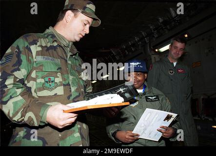 C-17 Frachtraum Interieur, mittlere Aufnahme, rechte Vorderansicht, Sraff Sergeant Arnold Parks, USAF, 97. Wartungsgeschwader, Altus Luftwaffenstützpunkt, Oklahoma, gibt dem 11 Jahre alten Krebspatienten Delray Simmons, dem ersten ausgewählten Kind für das Programm "Pilot für einen Tag", ein Geschwader-T-Shirt. Ein Blick auf SSGT Brian Williams, USAF, der das Programm „Pilot A Day“ entwickelt hat. Das Programm führt eine Person für einen Piloten durch einen normalen Tag. Basis: Luftwaffenstützpunkt Altus Bundesstaat: Oklahoma (OK) Land: Vereinigte Staaten von Amerika (USA) Stockfoto