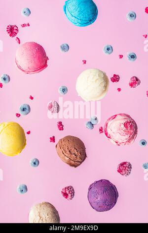 Fallende Eisschaufeln und Beeren auf rosa Hintergrund. Levitation von Lebensmitteln. Buntes Eis Kunst Foto. Stockfoto