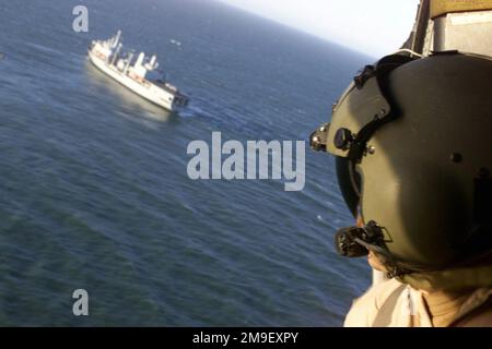 US Air Force Technical Sergeant Mark Cook, ein Pararescueman, der der 41. Rettungsschwadron am Luftwaffenstützpunkt Moody, Georgia, zugeteilt wurde, beobachtet das Fort Victoria Class Fleet Replenishment Ship, RFA (Royal Fleet Auxiliary) FORT GEORGE (A 388), Hilfsschiff der britischen Flotte, das vor der Küste Mosambiks bei Machanga vor Anker liegt, fährt unter dem USAF HH-60G „Pave Hawk“ Helikopter und kehrt nach Lieferung der Vorräte in die Stadt Machanga nach Beira zurück. Bisher haben die an Operation Atlas Response beteiligten Luftfahrzeuge der Joint Special Operations Task Force mehr als 71 Tonnen humanitärer Hilfe geliefert Stockfoto