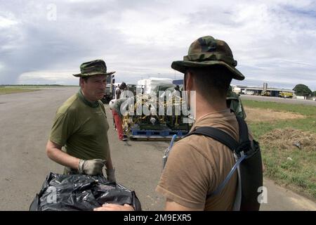 Ansicht von der rechten Vorderseite mittlere Nahaufnahme als British Flight Sergeant Tony Geerah (Left), ein Air Cargo SPECIALIST, dem United Kingdom Mobility Air Movement Squadron ( UKMAMS ), Royal Air Force, (RAF), Lyneham, Vereinigtes Königreich, zugewiesen. Spricht am 16. März 2000 am internationalen Flughafen in Maputo, Mosambik, Afrika, mit dem US Air Force Captain Jeff Burrell (rechts), Offizier für Logistikpläne und Frachtbewegungen, vom Hauptsitz der US Air Forces Europe, Logistikabteilung, Luftwaffenstützpunkt Ramstein, Deutschland, über Parkplätze für ankommende Flugzeuge. Sie und ihre Teams sind im Einsatz Stockfoto