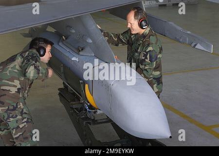 Ein Profil mittlerer Nahaufnahme aus einem hohen Blickwinkel, während USAF-STAFF Sergeant Frank Furtado (links) und MASTER Sergeant Bradly Haynie (rechts) eine AGM-154A Joint Stand-off Weapon (JSOW) hochladen, auf dem Pylon eines F-16CJ-Kampfflugzeugs auf dem Shaw Air Force Base, South Carolina. Der 20. Kampfflügel auf der Shaw Air Force Base ist die erste Air Force F-16 Einheit, die das Joint Stand-off Weapon (JSOW)-System implementiert hat. Das Waffenladesteam der 20.-Einsatzgruppe, Abteilung Waffenstandardisierung, wird derzeit zertifiziert, um das neue Waffensystem hochzuladen. Luftwaffenstützpunkt Shaw, Bundesstaat: Stockfoto