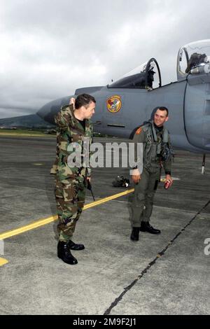 Rechte Vorderansicht Mittleres Bild, während US Marine Captain Mark Elfers (rechts) (VMA 223) mit LTC Darryl Burke (links) (Commander, 65 OSS) nach der Ankunft von CAPT Elfers in Lajes Field, Azoren, Portugal spricht. VMA 223, aus Ewa Oahu, Hawaii, hielt auf dem Weg nach Griechenland in Lajes an. Das linke Profil des Cockpits und des Nasenabschnitts bei einer US Marine AV-8B Harrier ist im Hintergrund zu sehen. Basis: Lajes Field State: Azoren Land: Portugal (PRT) Stockfoto