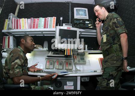 Gerade auf der linken und rechten Seite nimmt der US Air Force Captain Freddy Walker (links) und STAFF Sergeant Chris Cafmeyer, 731. Munitions Support Squadron, wichtige Informationen von der USAFE-Kommandozentrale auf und empfängt sie. SSGT Cafmeyer ist der NCOIC der Kommandozentrale. Zusätzlich zu einer regulären Arbeitswoche haben die Beamten in Araxos eine 24-Stunden-Schicht in der Kommandozentrale, die liebevoll als "Loch" bezeichnet wird. Basis: Araxos Air Base Land: Griechenland (GRC) Stockfoto