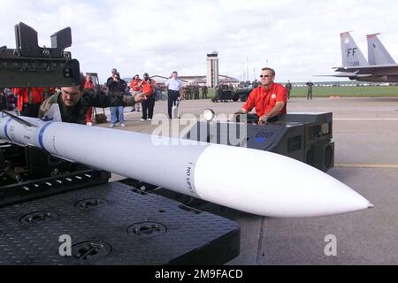 STAFF Sergeant Mark Swain, Weapons Load Crew CHIEF, 71. Kampfgeschwader, Langley Air Force Base, Virginia, sichert ein Sicherheitsband an einer AIM 120 Advanced Air-to-Air Rakete (AMRAAM) als Dale Jarrett, 1999 NASCAR Winston Cup Champion, Er fährt den Bombenhubwagen während eines Ladungswettbewerbs auf dem Luftwaffenstützpunkt Langley, Virginia. Basis: Luftwaffenstützpunkt Langley Bundesstaat: Virginia (VA) Land: Vereinigte Staaten von Amerika (USA) Stockfoto