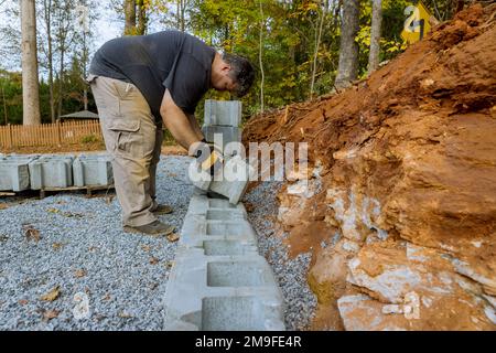 Bauarbeiter baute Betonblöcke zur Wandbefestigung in der Nähe des neuen Hauses auf der Baustelle Stockfoto