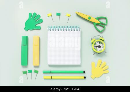 Sammlung von Schulpapier, Notizblock, Schere, Marker, Wecker, Gelbe und grüne Schaltflächen auf grünem Hintergrund. Bildung oder Kreativität Stockfoto