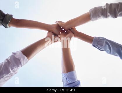 Nutzen wir den Tag. Ein kleiner Winkel von einer unerkennbaren Gruppe von Geschäftsleuten, die zusammenstehen und sich gegenseitig eine High Five geben. Stockfoto