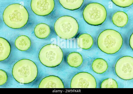 Frische Gurkenscheiben auf blauem Hintergrund, flach liegendes Bild über Kopf. Gesundes Bio-Food-Design Stockfoto