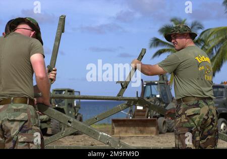 Sergeant Sean Ropp vom 8. Ingenieurstützbataillon, 2. Fleet Service Support, Charlie Company, befestigt Zeltstützen, während Oberleutnant Brian Briggs des US Marine Corps während der Zeltstädte, die einen Teil der neuen HORIZONTE der Operation zusammenbauen, aufmerksam zusieht. Etwa 100 Mitarbeiter der Marine, Armee und Luftwaffe haben im Rahmen der New Horizons nach Caevi, St. Lucia, entsandt. Im Rahmen der Operation werden zwei Aufgaben durchgeführt, nämlich Bereitschaftsausbildung und humanitäre Hilfe in der Karibik und in Lateinamerika. Betreff Operation/Serie: NEW HORIZONS Basis: CaerivCountry: Saint Lucia (LC Stockfoto