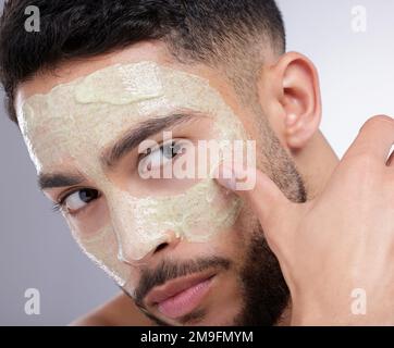 Die Vorteile der Hautpflege sind endlos. Ein junger Mann, der eine Gesichtsmaske vor einem Studiohintergrund aufbringt. Stockfoto