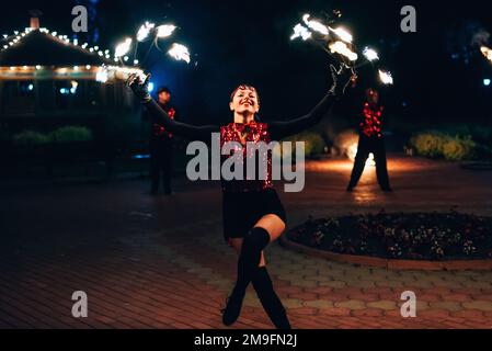 SEMIGORYE, OBLAST IVANOVO, RUSSLAND - 26. JUNI 2018: Feuershow. Das Mädchen dreht die feurigen Fackeln. Gefährliche, fantastische Nachtaufführung Stockfoto