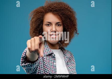 Lächelnde Frau, die mit dem Finger auf jemanden zeigt Stockfoto