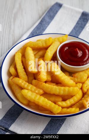 Hausgemachte ungesunde Crinkle Pommes mit Ketchup auf einem Teller, Seitenansicht. Stockfoto