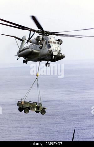 Ein Helikopter des US Marine Corps (USMC) CH-53E Super Hallion verwendet einen Hebegurt, um ein Mehrzweckfahrzeug mit hoher Mobilität (HMMWV) während der Übung KERNEL BLITZ 2001 aus dem Cockpit der USS PELELIU (LHA 5) zu heben. Betreff Betrieb/Serie: KERNEL BLITZ 2001 Basis: USS Peleliu (LHA 5) Stockfoto