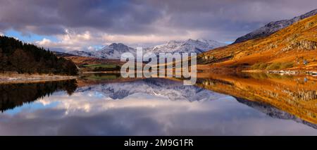 Ein Panoramablick auf die schneebedeckten Snowdon Horseshoe Berge in einem See im Snowdonia National Park, Nordwales Stockfoto