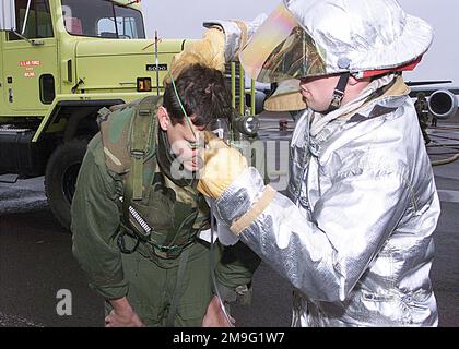 AIRMAN First Class (AFC) Jarred Mumma, ein Feuerwehrmann der 92. Bauingenieurstaffel, assistiert First Lieutenant Rob Randall der 97. Luftbetankungsstaffel nach einem simulierten Flugzeugbrand während der ORI-ÜBUNGSKRISE REACH 01-49 am Luftwaffenstützpunkt Fairchild. AFC Mumma trägt eine aluminisierte Wahlausrüstung oder einen Crash/Fire/Rescue Suit (CFR), der von Feuerwehrleuten in Anwendungen mit hoher Hitze verwendet wird. Betreff Operation/Serie: CRISIS REACH 01-49 Basis: Airway Heights Bundesstaat: Washington (WA) Land: Vereinigte Staaten von Amerika (USA) Stockfoto