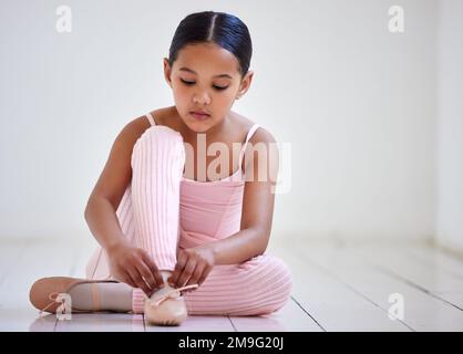 Ich bereite mich auf den Tanz vor. Ein kleines Mädchen, das in einem Ballettstudio Schuhe anzieht. Stockfoto