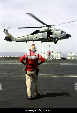 US Navy CHIEF Warrant Officer James Osmond beobachtet, wie US Navy Aviation Ordnanceman Second Class Toby Snowden als Sicherheit für US Navy Aviation Ordnanceman Third Class Michael Tune fungiert, als sie Container für Kampfmitteltransporte an einen SH-60F Antisubmarine Warfare Helicopter auf dem Flugdeck der USS HARRY S. haken TRUMAN (CVN 75). Truman ist auf Station im Persischen Golf, um die Operation SÜDWACHE zu unterstützen. Betreff Betrieb/Serie: SÜDLICHE WACHSTATION: USS Harry S. Truman (CVN 75) Stockfoto