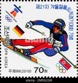 Nordkoreanische Briefmarke aus dem Jahr 2010 anlässlich der Olympischen Winterspiele in Vancouver, mit einem Skiläufer und der deutschen und DVRK-Flagge. Stockfoto
