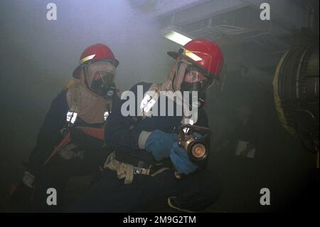 US Navy Aircrew Survival Equipmentman Third Class Jason Longmore und US Navy Personnelman Third Class Errick Steinwand bekämpfen ein Feuer im Jet Shop während einer allgemeinen Quartierübung an Bord der USS HARRY S. TRUMAN (CVN 75) Während des letzten Tages des Flugzeugträgers auf Station im Persischen Golf während der Operation SÜDWACHE. Betreff Betrieb/Serie: SÜDLICHE WACHSTATION: USS Harry S. Truman (CVN 75) Stockfoto