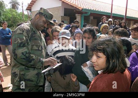 US Army STAFF Sergeant Donnie White, vom 21. General Hospital, Saint Louis, Missouri, verteilt kleine Smiley-Gesichtsaufkleber an die lokalen Kinder außerhalb der Canada San Juan Klinik, Paraguay, während sie in der Schlange warten, um vom medizinischen Personal gesehen zu werden, während Training NEUE HORIZONTE. Die kombinierte Task Force Guarani Springs führt Ingenieure und medizinische Operationen in Paraguay durch und ermöglicht so eine gemeinsame Ausbildung. Die Task Force wird die Infrastruktur von vier Schulen, vier Brunnen, zwei medizinischen Kliniken renovieren, bauen und verbessern und mehrere medizinische Übungen (MEDRETES) durchführen, an Stockfoto