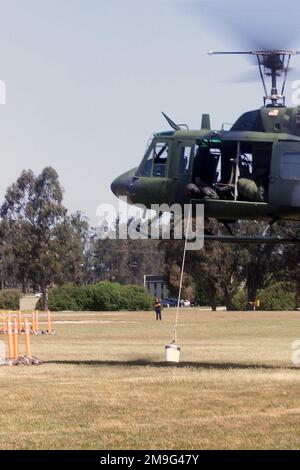 010508-F-7685H-020. [Complete] Scene Caption: Führung der UH-1N Iroquois durch den Piloten, Scanner First Lieutenant Matt Cotreras, USAF, 37. Helicopter Flight, 90. Space Wing, F.E. Warren Air Force Base, Wyoming, ruft die Bewegungen an, wenn sie sich einem der Hindernisse nähern. Ziel ist es, einen Eimer Wasser, der aus dem Hubschrauber herabhängt, durch die Hindernisse auf dem Platz zu führen, ohne den Inhalt zu verschütten. Der Helicopter Hover Competition Course wird mit einer dreiköpfigen Crew, einem Piloten und einem Kopiloten mit einem Flugingenieur oder einem zusätzlichen Piloten als Scanner geflogen. Sowohl Pilot als auch Kopilot fliegen den gesamten Kurs an Stockfoto