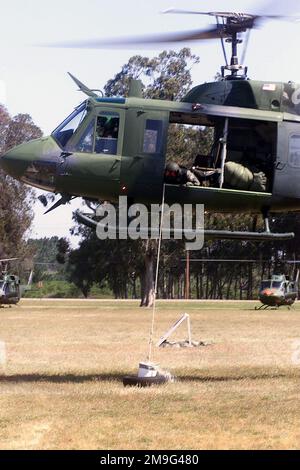 010508-F-7685H-021. [Complete] Scene Caption: Führung der UH-1N Iroquois durch den Piloten, Scanner First Lieutenant Matt Cotreras, USAF, 37. Helicopter Flight, 90. Space Wing, F.E. Warren Air Force Base, Wyoming, ruft die Bewegungen, wenn sie auf das Ziel fallen, einen Eimer Wasser, der etwas Inhalt verschüttet. Ziel ist es, einen Eimer Wasser, der aus dem Hubschrauber herabhängt, durch die Hindernisse auf dem Platz zu führen, ohne den Inhalt zu verschütten. Der Helicopter Hover Competition Course wird mit einer dreiköpfigen Crew, einem Piloten und einem Kopiloten mit einem Flugingenieur oder einem zusätzlichen Piloten als Scanner geflogen. Beides Stockfoto