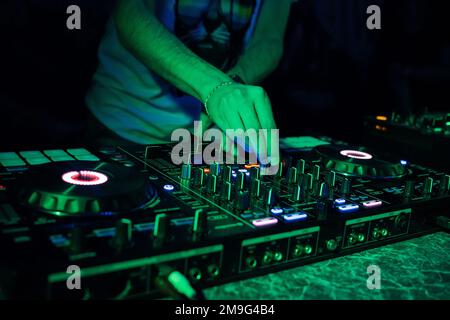 Spielt DJ-Musik auf einem professionellen Mixerboard in einem Nachtclub Stockfoto