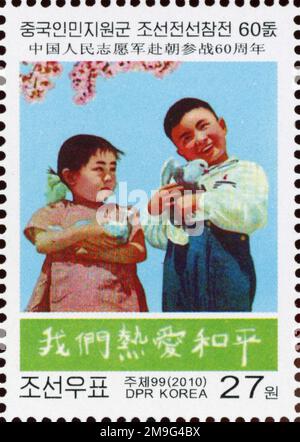 2010 Nordkorea-Stempel. 60. Jahre chinesische Hilfe im Koreakrieg. Kinder mit Friedentaube Stockfoto