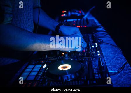 Spielt DJ-Musik auf einem professionellen Mixerboard in einem Nachtclub Stockfoto