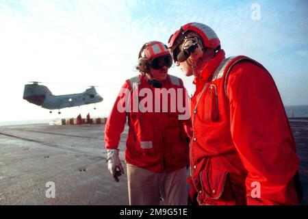 DER US Navy AIRMAN Denver Foster erhält eine Nachricht vom US Navy CHIEF Warrant Officer Two Hames Ausman während einer Waffenentladung auf das Flugdeck der USS HARRY S. TRUMAN (CVN 75). Ein CH-46 Sea Knight Hubschrauber ist im Hintergrund zu sehen. Basis: USS Harry S. Truman (CVN 75) Stockfoto