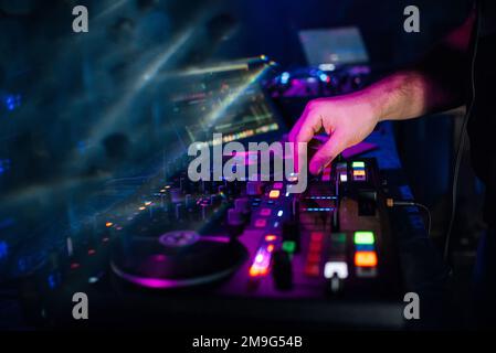 Auf einer Party in einem Nachtklub spielt und mischt DJ Musik auf einem modernen Musikcontroller Stockfoto