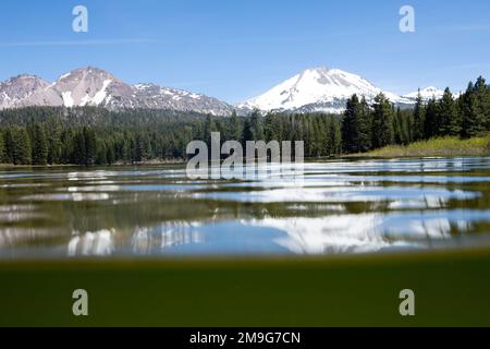 Seenoberfläche im Lassen Volcanic National Park mit schneebedeckten Vulkanen im Hintergrund, Kalifornien, USA Stockfoto