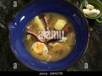 Traditionelle polnische Zurek Sour Suppe aus Roggenmehl serviert mit Wurst und hart gekochten Eiern. Stockfoto