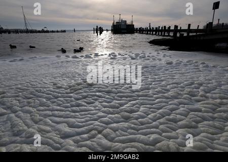 Rerik, Deutschland. 18. Januar 2023. Weißer Schaum auf dem Salzhaff scheint in die Sonne. Der heftige Wind der letzten Tage hatte das Wasser aufgewühlt. Im Norden dominiert ruhiges und teilweise sonniges Wetter. Kredit: Bernd Wüstneck/dpa/Alamy Live News Stockfoto