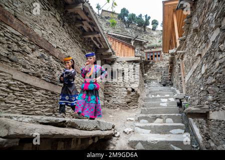 Two young girls wearing traditional attire on the street of a Kalash village, Bumburet Valley, Pakistan Stock Photo